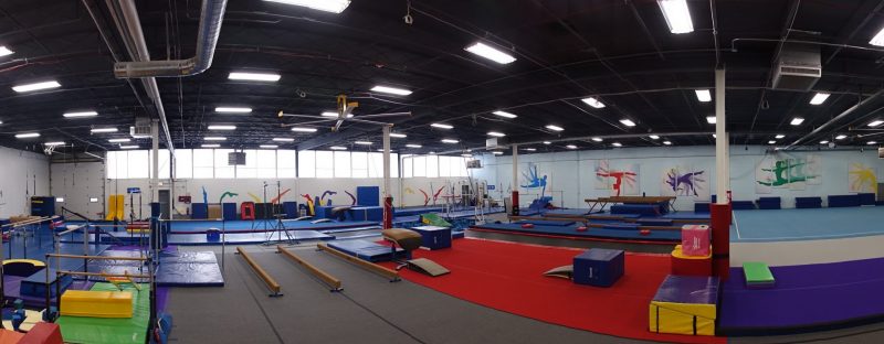 A panoramic photo of a gymnastic facility, showcasing the different kinds of equipment important to the sport.