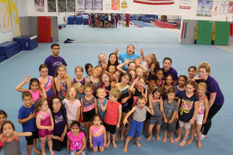 A group of children pose for a silly picture after a day of gymnastics camp.